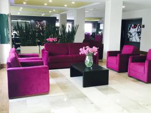 eine Lobby mit lila Sofas und einer Blumenvase in der Unterkunft Hotel HAUS Ixtaczoquitlán in Orizaba