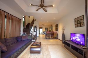 a living room with a purple couch and a flat screen tv at Maenam Hills Samui in Koh Samui 
