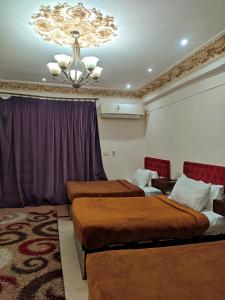 een hotelkamer met 2 bedden en een kroonluchter bij SARAYA AWAD HEGAZI STREET- families only in Alexandrië +160 foto's