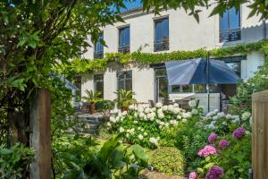 a garden with an umbrella in front of a building at Escale Rochelaise, chambre avec access spa et sauna in La Rochelle