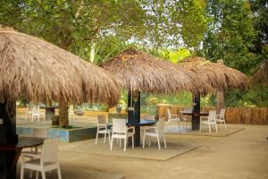 Un grupo de mesas y sillas bajo sombrillas de paja. en Ella Forest Bath, en Ella
