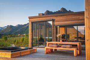a house with a hot tub and benches on a deck at Seafront Luxury Villa near Henningsvær in Kleppstad