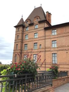 a large brick building with flowers in front of it at Chambre Cosy 3 in Montauban