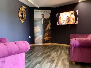 a room with two purple couches and a tv on a wall at Le 007 Refuge -Rurale gîte élégant piscine privée in Queyssac