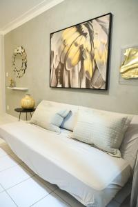 a bedroom with a white bed with a painting on the wall at Apartamento Atalaia Aracaju 3 quartos in Aracaju