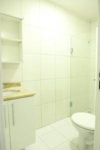 a white bathroom with a toilet and a sink at Apartamento Atalaia Aracaju 3 quartos in Aracaju
