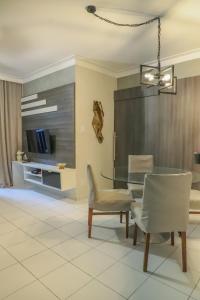 a dining room with a table and chairs and a tv at Apartamento Atalaia Aracaju 3 quartos in Aracaju