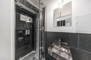 a bathroom with a shower with a sink and a mirror at LS 3-Apartments Hauptbahnhof Halle in Halle an der Saale
