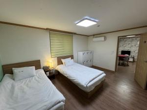 a hotel room with two beds and a table at Suncheon Doran Doran House in Suncheon