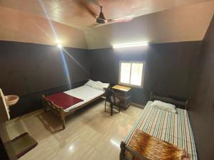 a room with a bed and a table and a window at Athirappilly Ambady Resort in Athirappilly