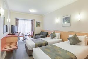 a hotel room with two beds and a table at The Waverley International Hotel in Glen Waverley
