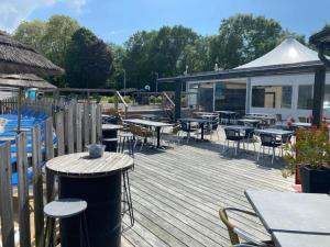 a wooden deck with tables and chairs and a building at Charmant Mobil-home 3 chambres de Valérie et Hermann Camping 4 étoiles in Clohars-Carnoët