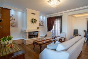 Una sala de estar con muebles blancos y chimenea. en Zinovia's Luxury House, en Caristo