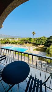 un balcone con tavolo, sedie e piscina di Saint-Florent studio vue piscine a Saint-Florent Altre 3 foto