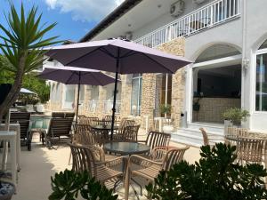 a patio with tables and chairs and an umbrella at Hotel Pighi in Kriopigi
