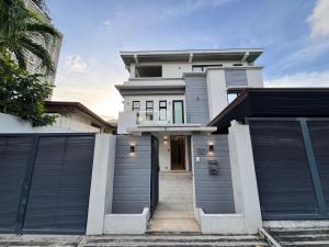 a white house with two garage gates in front of it at Halika Villa & Capitolo events place near BGC in Manila