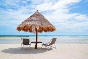 two chairs and an umbrella on the beach at Nice Sea Resort in Srithanu