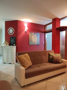 a couch in a living room with a red wall at Spacious 3Bedroom Apartment in Nardò, Apulia, Balcony, AC, Wi-Fi in Nardò