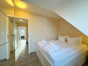 une chambre avec un lit avec des draps blancs et des oreillers dans l'établissement Ferienwohnung in Tinnum mit Balkon, à Tinnum