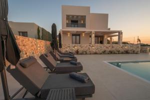 eine Gruppe von Liegestühlen und ein Swimmingpool in der Unterkunft Villa Jaubelli Bliss in Platánion
