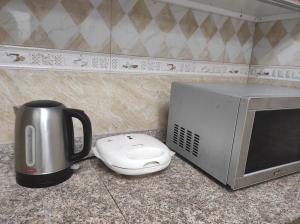 a coffee maker and a microwave on a counter at Elegant Ap in Muscat