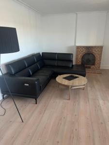 a black leather couch in a living room with a fireplace at Lækker lejlighed på havnefronten 1 in Nakskov