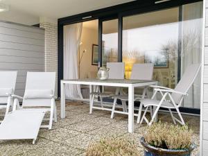 a white table and chairs on a patio at Ferienwohnung mit Terasse Haus Calma in Wenningstedt