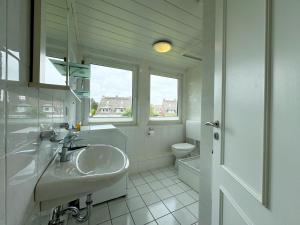 a white bathroom with a sink and a toilet at Ferienwohnung in Tinnum auf Syt in Tinnum
