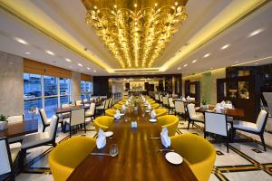 a dining room with a long table and yellow chairs at Jannah Burj Al Sarab in Abu Dhabi