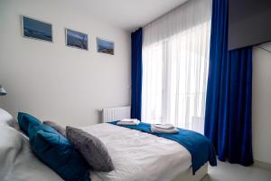 a bedroom with a bed with blue curtains and a window at Lulu Apartments - DEEP BLUE LAGOON apartament dwupokojowy - parking, Netflix - 350m od plaży! in Grzybowo