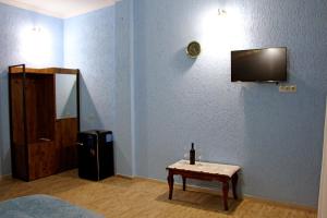 Habitación con TV y mesa con botella de vino. en Kolkhis Ezo, en Chʼardakhi