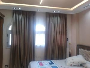 ein Schlafzimmer mit einem Bett und einem Fenster mit Vorhängen in der Unterkunft Apartment in Madinaty Cozy in Madinaty