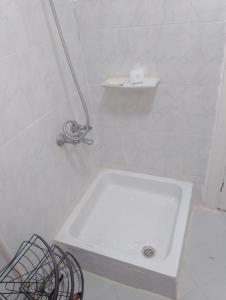 eine weiße Badewanne in einem weiß gefliesten Bad in der Unterkunft Apartment in Madinaty Cozy in Madinaty