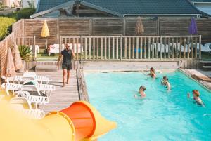 a man walking in a swimming pool with people in it at Camping calme En Charente Maritime in Surgères