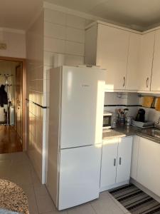 a kitchen with a white refrigerator and white cabinets at Apartamento de Férias in São Félix da Marinha +5 photos