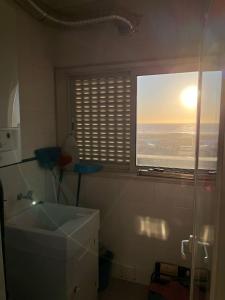 a bathroom with a sink and a window with the sunset at Apartamento de Férias in São Félix da Marinha