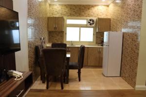 a kitchen with a table and a white refrigerator at القصر الضيافة 2 in Khamis Mushayt