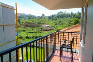 a balcony with a chair and a view of a field at Cheerful Chalet in Kodaikānāl