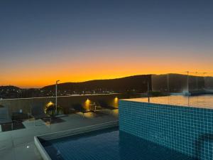 a swimming pool on top of a building with a sunset at Hotel em CABO FRIO Cond Royale - Av N S Assunção 239, bairro Passagem - un 229 in Cabo Frio