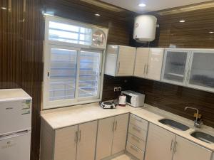 a kitchen with white cabinets and a sink and a window at شالية حلا in Khamis Mushayt