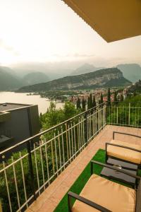 a balcony with chairs and a television and a view at Panoramic Lake View Apartment in Nago-Torbole