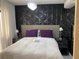 una camera da letto con un grande letto bianco con cuscini viola di Morada Supreme Itaim Bibi - Flat Duplo a San Paolo Altre 30 foto