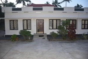 a white house with a front porch and a door at Tranquil Haven - An Ayur Escape Retreat in Kāyankulam +20 photos