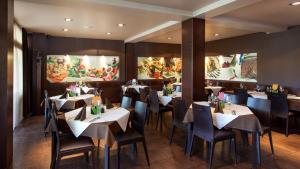 a restaurant with tables and chairs and paintings on the walls at Hotel Pomaranča in Ptuj