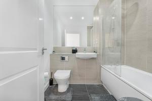 a bathroom with a toilet and a sink and a bath tub at Luxury 2BR minutes from City and Station - Free Parking, WiFi, Netflix in Dartford +27 photos