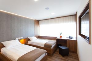 ein Hotelzimmer mit 2 Betten und einem TV in der Unterkunft Hotel Pomaranča in Ptuj