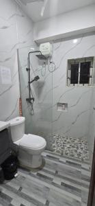 a bathroom with a toilet and a glass shower stall at Gold barbecue apartments in Tanga