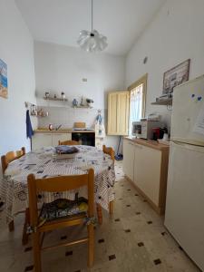 Una cocina con una mesa y un refrigerador blanco. en Casa Vacanze Amore, en San Vito lo Capo