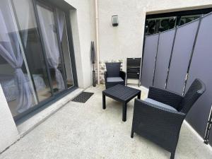 a patio with two chairs and a table and a window at Chambre indépendante avec terrasse in Romille