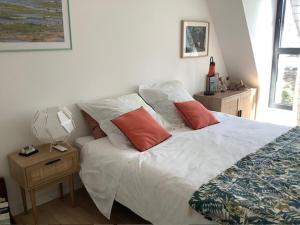 a bedroom with a white bed with orange pillows at LES AUGUSTINS, chambres d'hôtes, quartier historique, accueil 2 roues in Angers